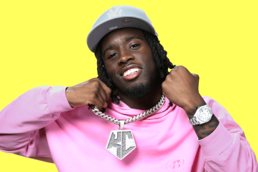 Kai Cenat in a pink hoodie against a yellow background.